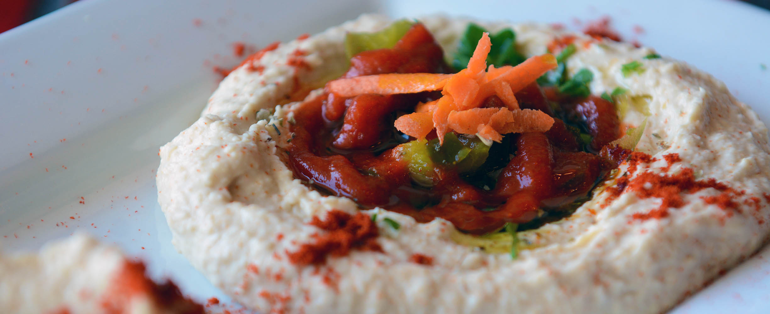 Hummus, a staple Meditearranean food, is customized and enhanced with bell peppers, olives, and other vegetables and spices. This makes a gourmet huumus!